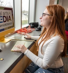 A young woman works at a computer at a 2024 on-campus Job Fair event