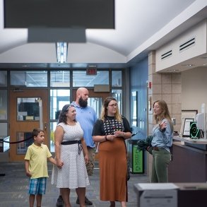 A prospective student with her parents and sibling on a campus tour of the library