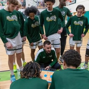 Men's basketball coach detailing the next play to his team