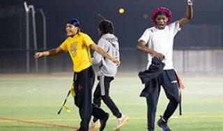 Students celebrating playing flag football on the turf field at night