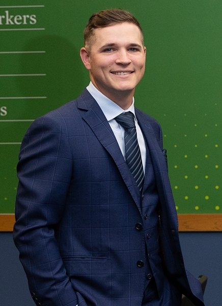 Brady Sausville, a business alum, standing in the Scoville Auditorium for a portrait photo